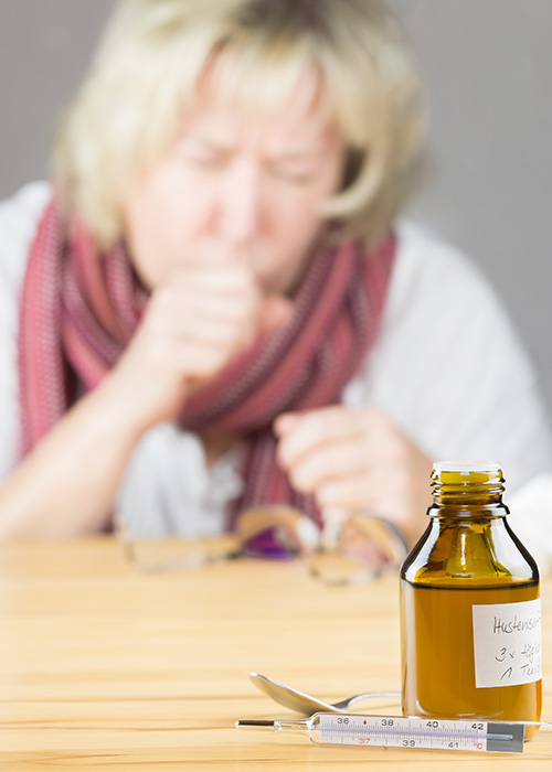 Femme qui tousse avec des antibiotiques autour d'elle