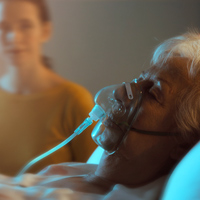 Personne en fin de vie allongée dans un lit d'hôpital avec une aide respiratoire