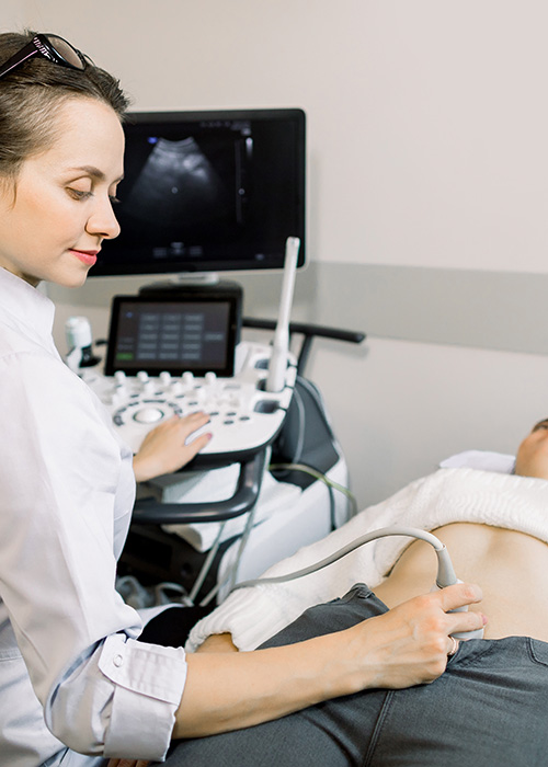 Médecin passant une sonde sur le bas ventre d'un patient pour une échographie des voies urinaires