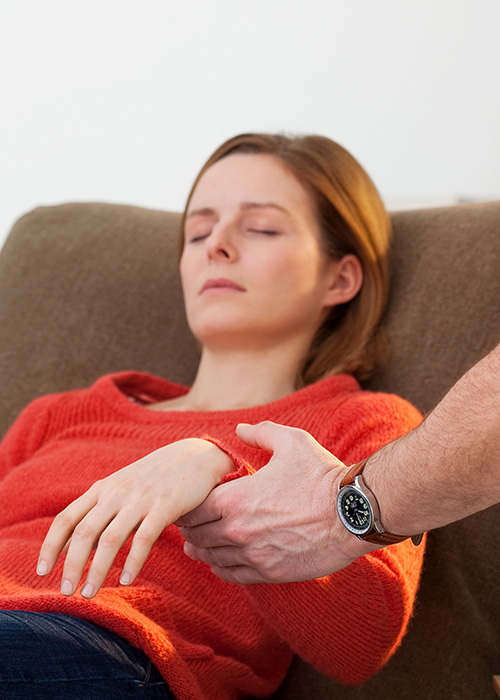Médecin tenant le poignet de sa patiente assise lors d'une séance d'hypnose
