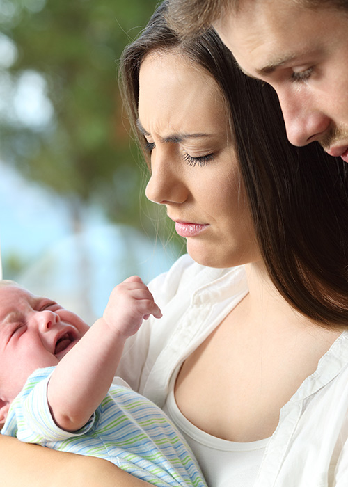 Jeune couple épuisé et impuissant face à un nourrisson qui pleure